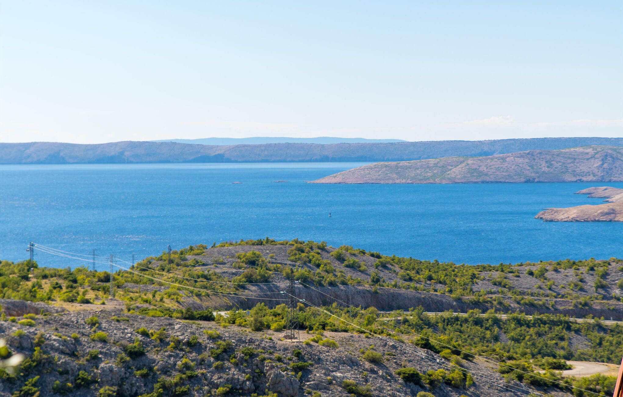 Eine Küstenlandschaft mit freiem Blick auf das Meer, felsigem Gelände und spärlicher Vegetation.