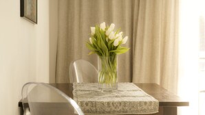 A table with a vase of white tulips and a clear glass, set against a beige curtain backdrop. - FEWO-KARLOTTA New 2-room / 5 min. Ammersee & Zentrum- LUXURY in the heart of Dieessen! (Diessen)
