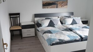 Ein Schlafzimmer mit einem Bett, einem Sessel, einem Nachttisch und einem Bild an der Wand.