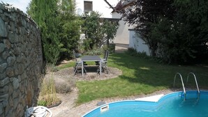 Ein Schwimmbecken mit einer Steinmauer und einem Tisch mit Stühlen im Hintergrund.