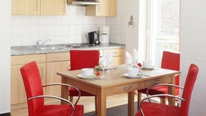 Eine moderne Küche mit Holzausstattung, einer Edelstahl-Dunstabzugshaube und einem Essbereich mit Tisch für vier Personen.