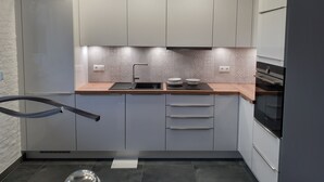 A modern kitchen with grey cabinets, a black countertop, and a stainless steel sink. - Detached holiday home in a quiet location, right on the Grevelingenmeer (Herkingen)