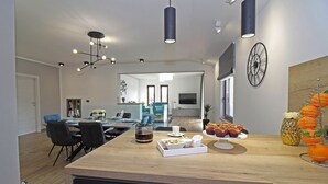A modern kitchen with a wooden countertop, a coffee machine, and a fruit bowl.