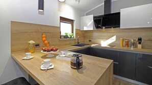 A modern kitchen with a wooden countertop, a coffee maker, and a fruit bowl.
