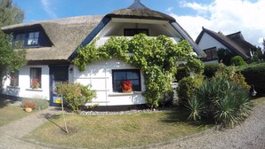 A traditional house with a thatched roof, white walls, and a balcony. - Landhaus Darss - in love with nature (Wieck a. Darß)
