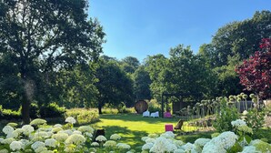 A garden with white hydrangea bushes, a wooden pergola, and a grassy lawn. - Holiday house at the lake *Pets*Art*Raft* Golf *Bathing lake*Canoe*Idyll (Crivitz OT Basthorst)
