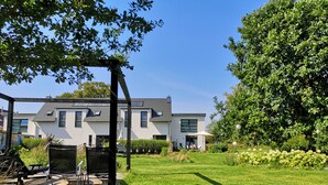 A modern house with a well-maintained lawn, outdoor seating area, and a pergola. - Holiday house at the lake *Pets*Art*Raft* Golf *Bathing lake*Canoe*Idyll (Crivitz OT Basthorst)