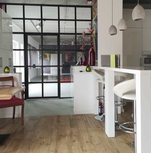 Una cocina moderna con piso de madera, muebles blancos y un ventanal grande.