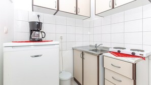 Una cucina compatta con mobili bianchi, una moka, un lavello e un fornello.