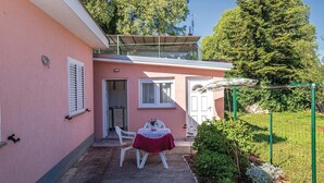 Un edificio rosa con un piccolo patio, un tavolo con tovaglia all'uncinetto e una sedia.