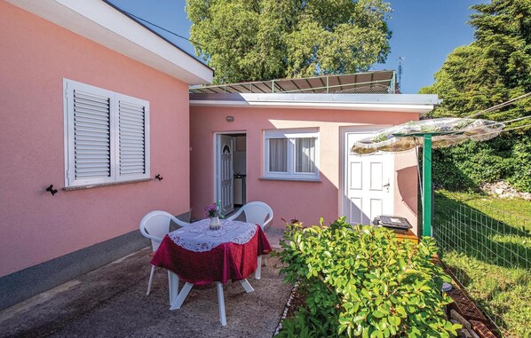 Une petite terrasse avec une table et des chaises, un espace extérieur abrité et un jardin.