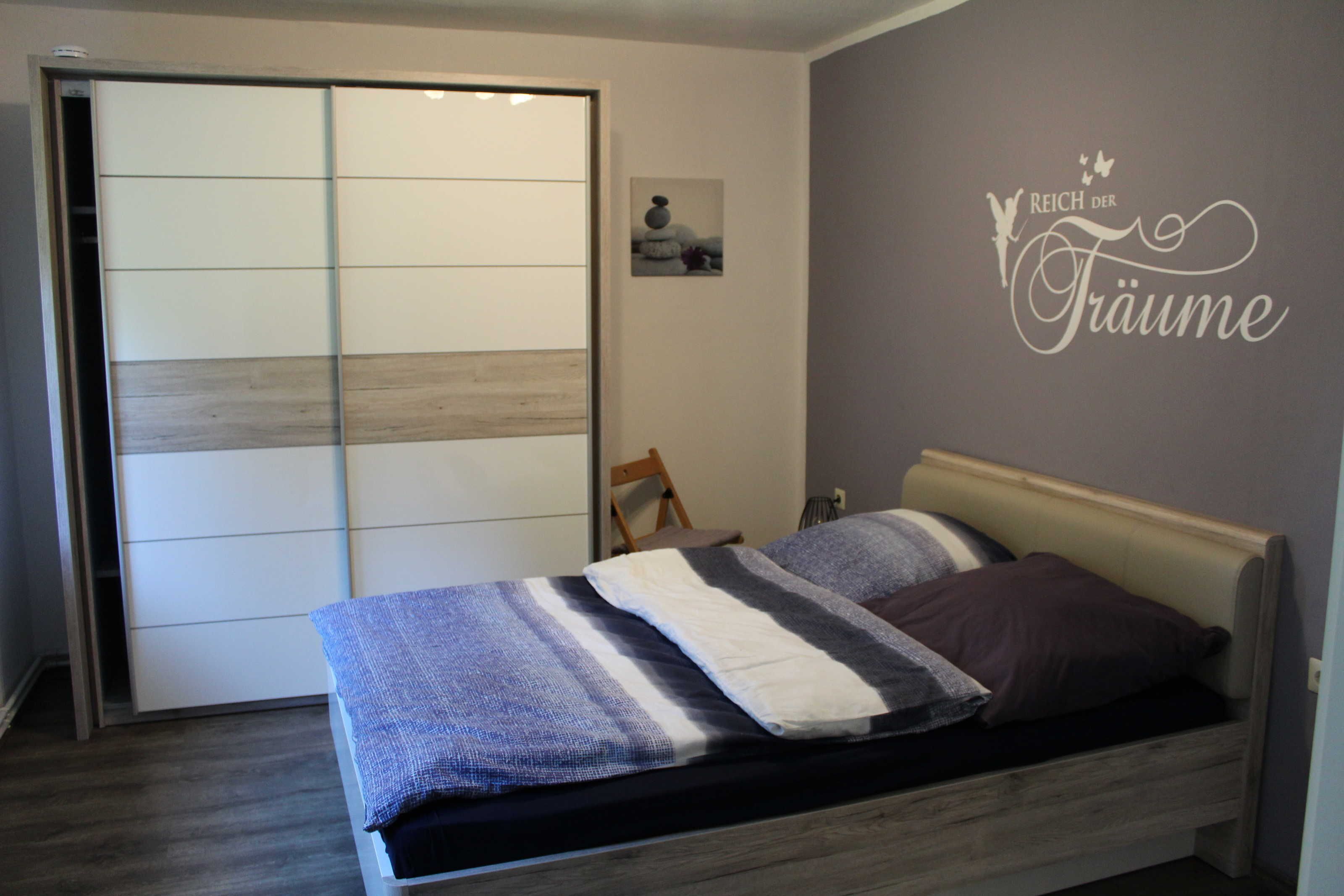 Un dormitorio con una cama, un armario y una pared con un letrero decorativo.