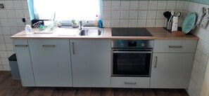 Una cocina moderna con horno empotrado, un lavabo y una encimera.