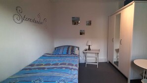 A bedroom with a bed, a desk, a chair, a wardrobe, and a small table. - Holiday house Hof Amelung (Bramstedt)
