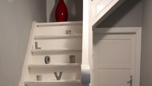 A white staircase with steps labeled with letters and a red vase at the top. - Holiday house Hof Amelung (Bramstedt)