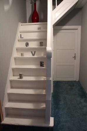 Una escala blanca amb graons marcats amb lletres i un vas vermell al capdamunt.