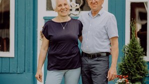 A man and woman standing in front of a blue building with a white door and windows. - Holiday house Hof Amelung (Bramstedt)