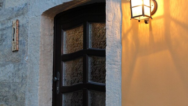 Un edificio con una puerta de madera oscura y una ventana pequeña con marco blanco.