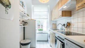 Eine moderne Küche mit weißen Schränken, einem Einbauofen, einer Spüle und einem Fenster für natürliches Licht.