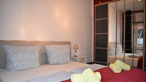 A neatly made bed with patterned pillows, a red blanket, and rolled towels. - Idyllic, central, quiet, high-quality apartment in an old building with excellent transport connections (Heidelberg)