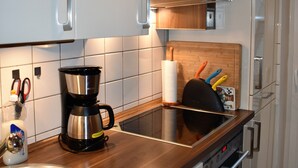 A modern kitchen with white cabinets, a stainless steel sink, a coffee maker, and a wooden countertop. - Idyllic, central, quiet, high-quality apartment in an old building with excellent transport connections (Heidelberg)
