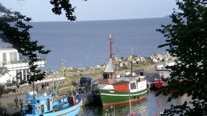 A harbor with boats docked, a building with a balcony overlooking the water, and a rocky shoreline. - Exclusive apartment, central location 10min to the harbor (Sassnitz)