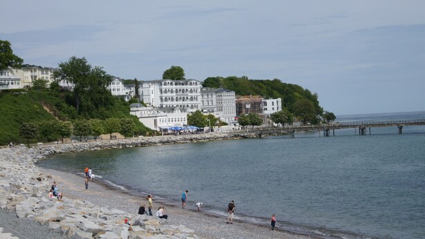 A coastal area with a rocky beach, a bridge, and buildings with balconies overlooking the water. - Exclusive apartment, central location 10min to the harbor (Sassnitz)