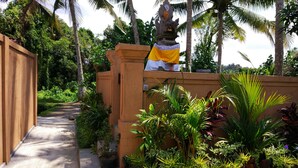 A pathway leading to a pool area with tropical plants and a statue. - Sujaya Villas (Ubud)