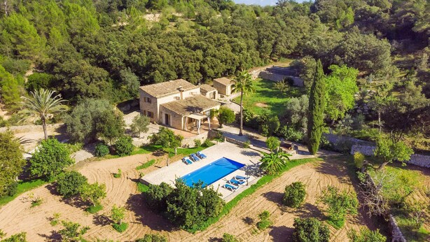 Eine Villa mit Swimmingpool, umgeben von üppiger Vegetation und Hügeln.