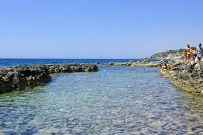 A rocky beach with clear water and a few people. - Nice detached house in a fantastic seafront location. No cleaning fees. (Siracusa)