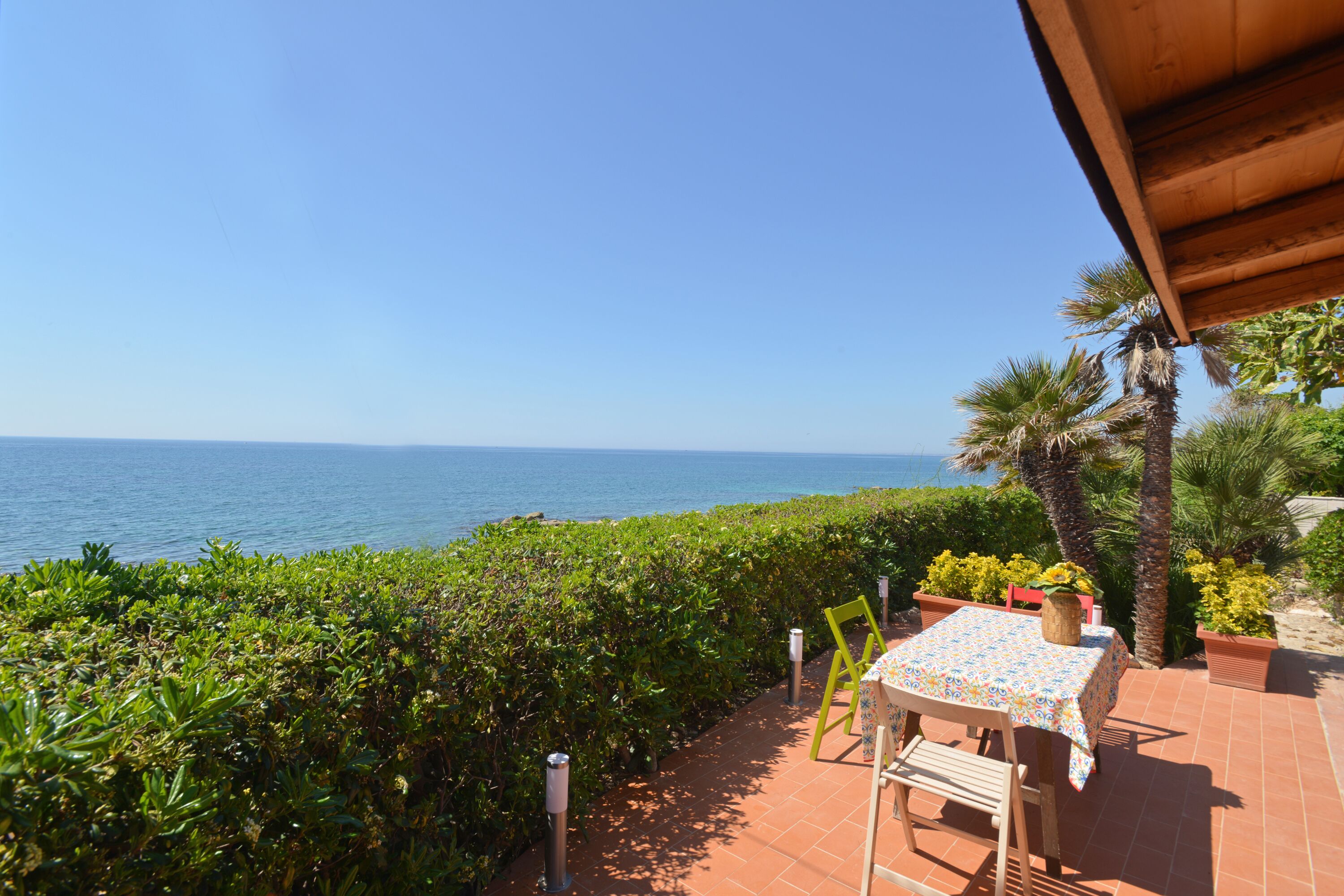 A patio with a table and chairs overlooking the sea.