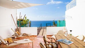 A patio with a view of the sea, featuring a table, chairs, and a small garden. - Jandia Mar 2 (Morro Jable)