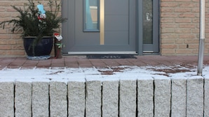A grey door with a glass panel, a mailbox with the number 27, and a potted plant on the brick wall. - Family-friendly apartment with a sun terrace of 45 sqm with WiFi (Horn-Bad Meinberg)
