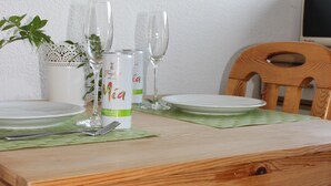 A wooden dining table with a green placemat, a white plate, a glass, and a can of 'Mojito' on it. - Family-friendly apartment with a sun terrace of 45 sqm with WiFi (Horn-Bad Meinberg)