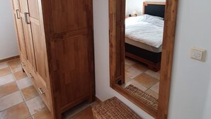 Ein Schlafzimmer mit einem Holzschrank, einem großen Spiegel und einem Korbwäschekorb auf dem Boden.