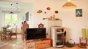 Ein gemütliches Wohnzimmer mit Fernseher, Holzmöbeln, Kamin und maritimer Dekoration.