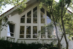 A house with a steeply pitched roof, multiple windows, and a tree in front. - Studio apartment in a dreamy and quiet garden in the immediate vicinity of the lake (Schondorf am Ammersee)
