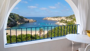 Un balcon donnant sur un paysage côtier, une table blanche et un bol jaune.