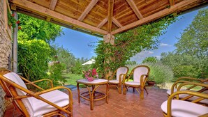 An outdoor patio with wicker furniture and a view of a garden.