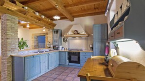 A kitchen with blue cabinets, a wooden island, and a brick wall.