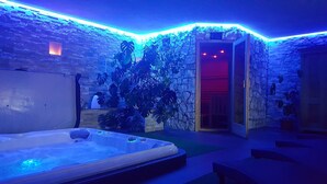 Ein Wellnessraum mit Whirlpool, Steinwänden und tropischen Pflanzen.