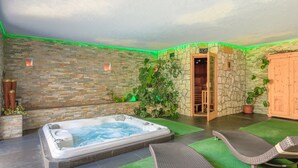 Ein Wellnessbereich mit Whirlpool, Liegestühlen und einer Steinwand mit Bepflanzung.