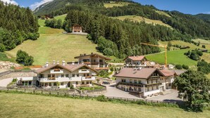Ein Bergresort mit mehreren Chaletgebäuden, einem zentralen Innenhof und Blick auf die umliegenden bewaldeten Hügel.
