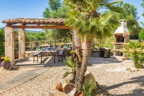 Eine Terrass mit Pergola, einem Backofen aus Ziegeln und einem Esstisch.