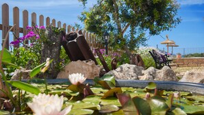 A garden with water lilies, a wooden fence, and a bench. - Finca Son Puca (Petra)