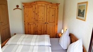 A bedroom with a double bed, a wooden wardrobe, and a framed picture on the wall. - Apartment for 2-3 people on the southern slope with View and possibility of excursions (Plankenfels)
