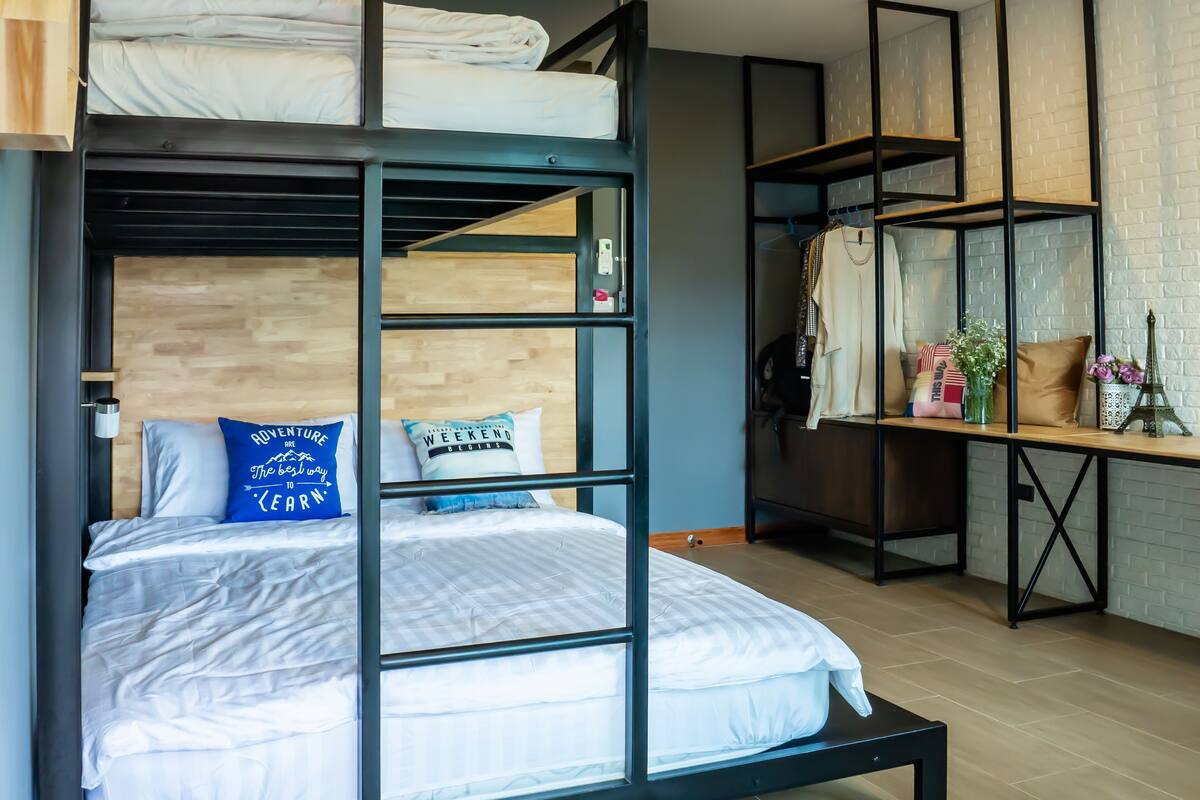 A bunk bed with a wooden headboard, a desk with a mirror, and a shelf with decorative items.