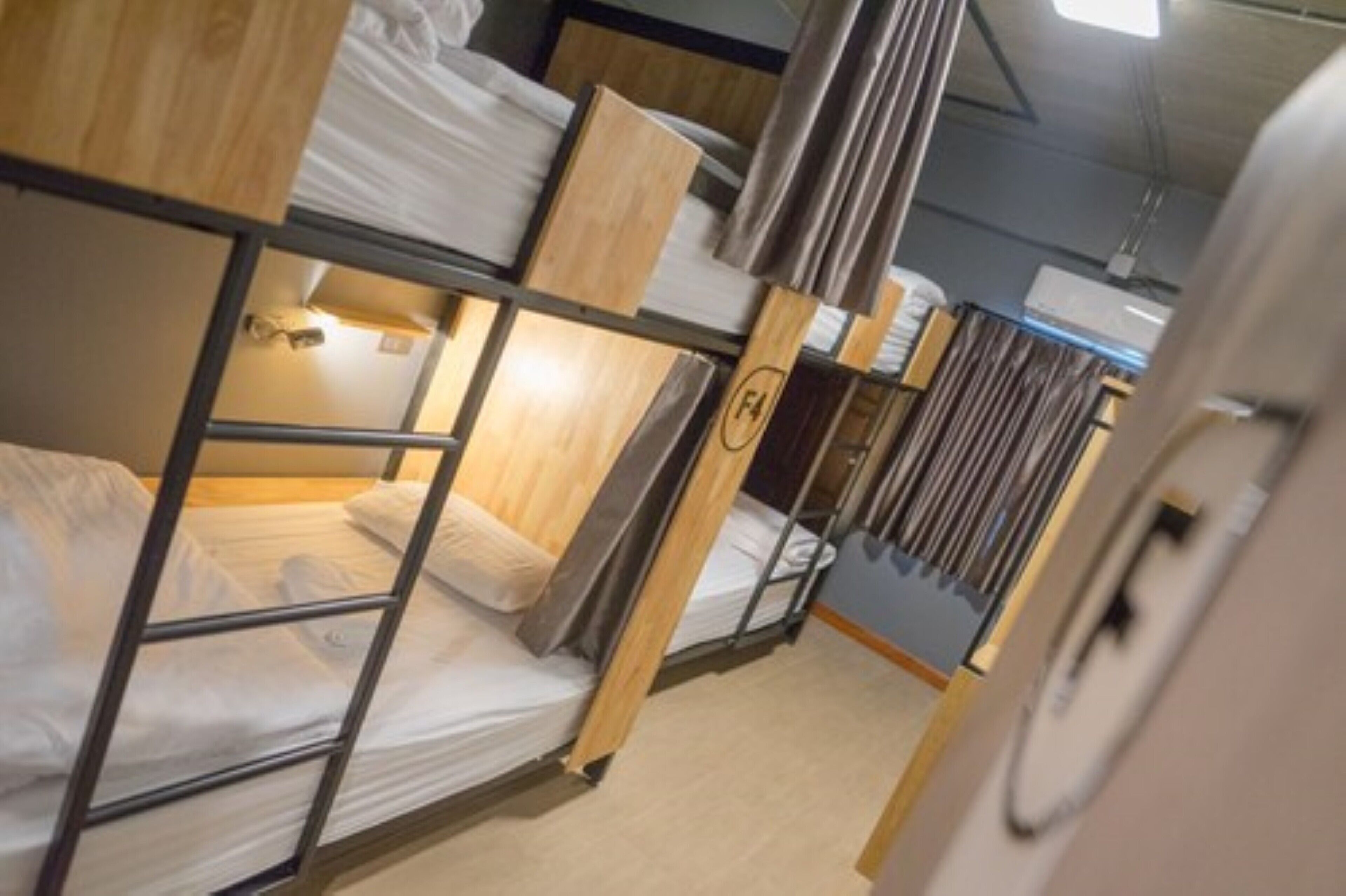 Dormitorio con literas de madera y ropa de cama blanca.