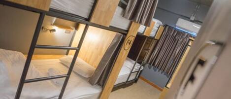 Dormitorio con literas de madera y ropa de cama blanca.