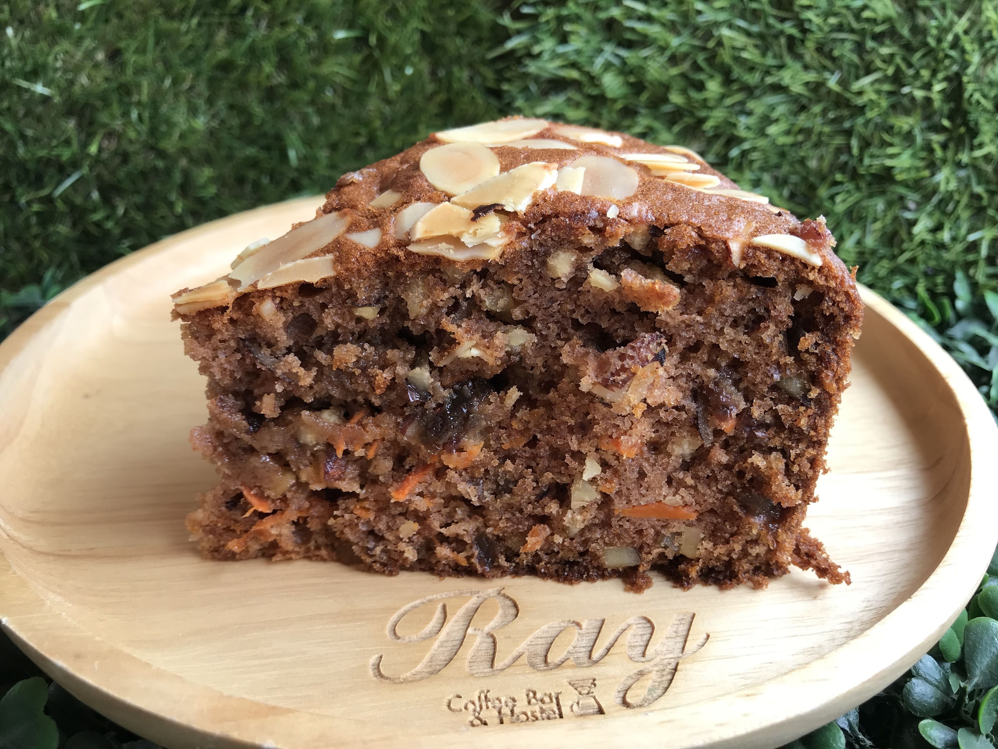 A slice of cake on a wooden plate with the inscription "Randy Coffee Bar & Hostel".